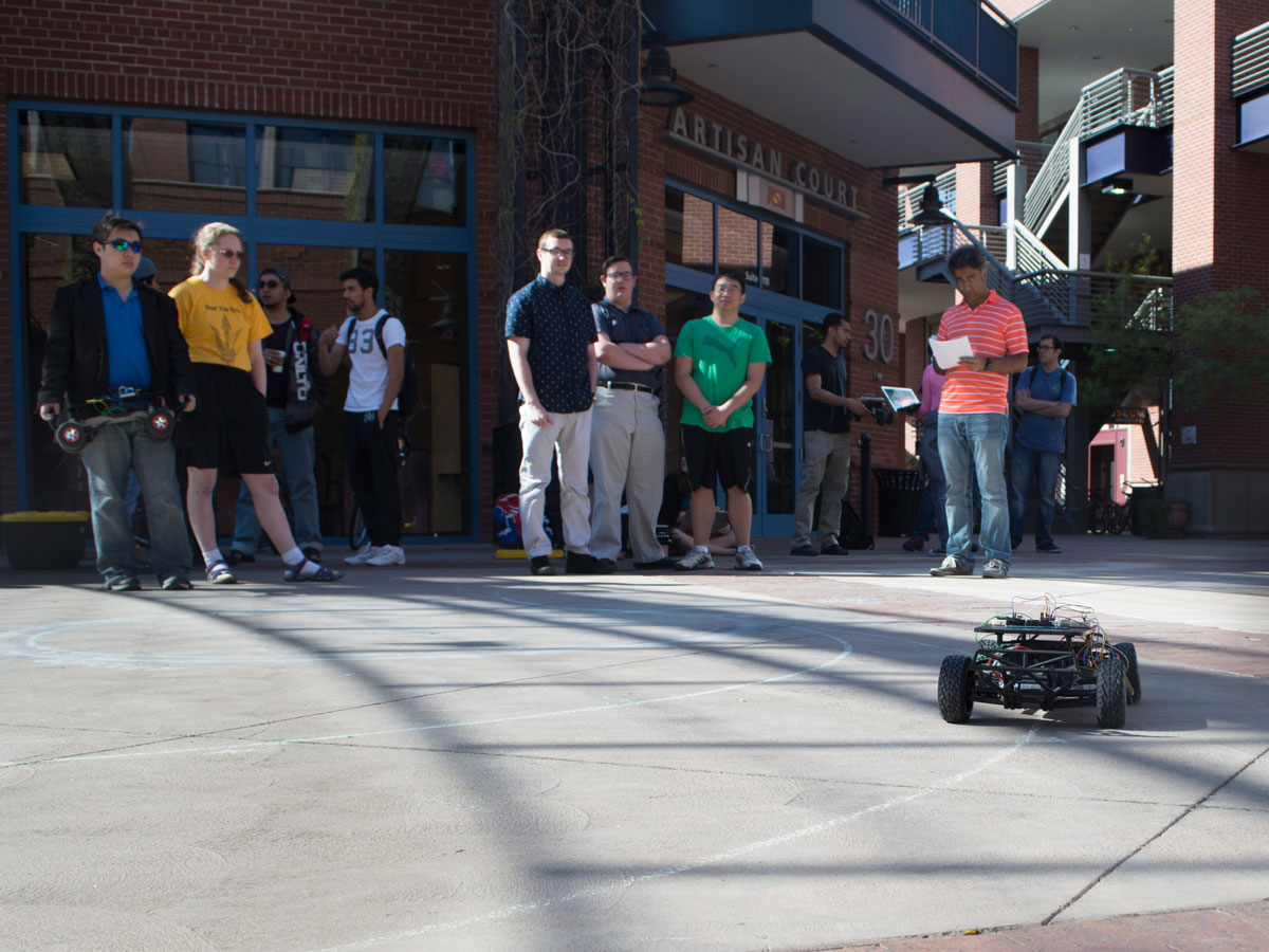 Students in Brickyard courtyard watch a demonstration of a self-navigating car