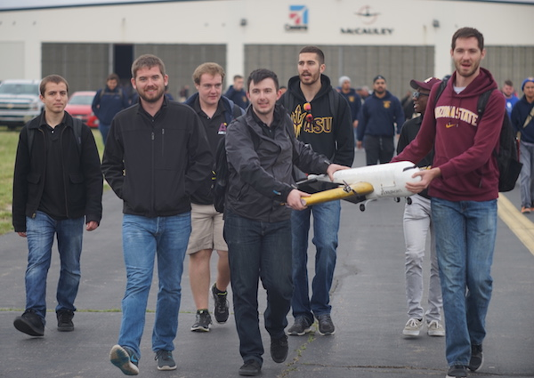 Air Devils team members carry their Manufacturing Support Aircraft to the starting line for one of the Design/Build/Fly competition flight missions. Pictured are (back row, left to right) Ivan Kruts, Nathan Stone, Brendan Hernandez, Walter Bonar; (front row, left to right) Jeffrey Kirkman, AJ Verbin, Ben Anderson.