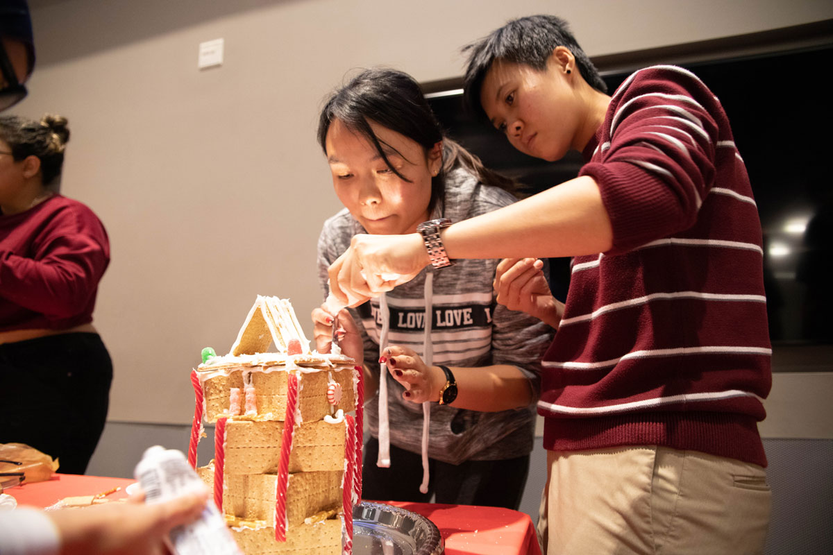 Two students building gingerbread house