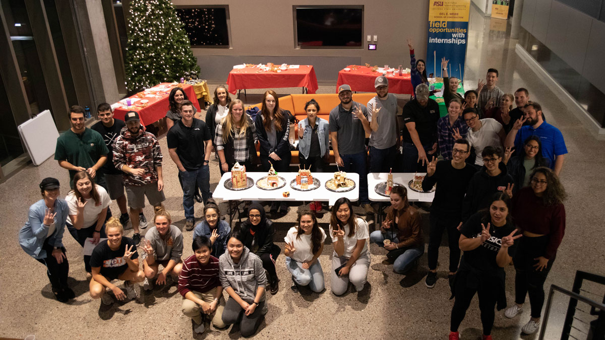 Group of about 40 students posing around gingerbread houses